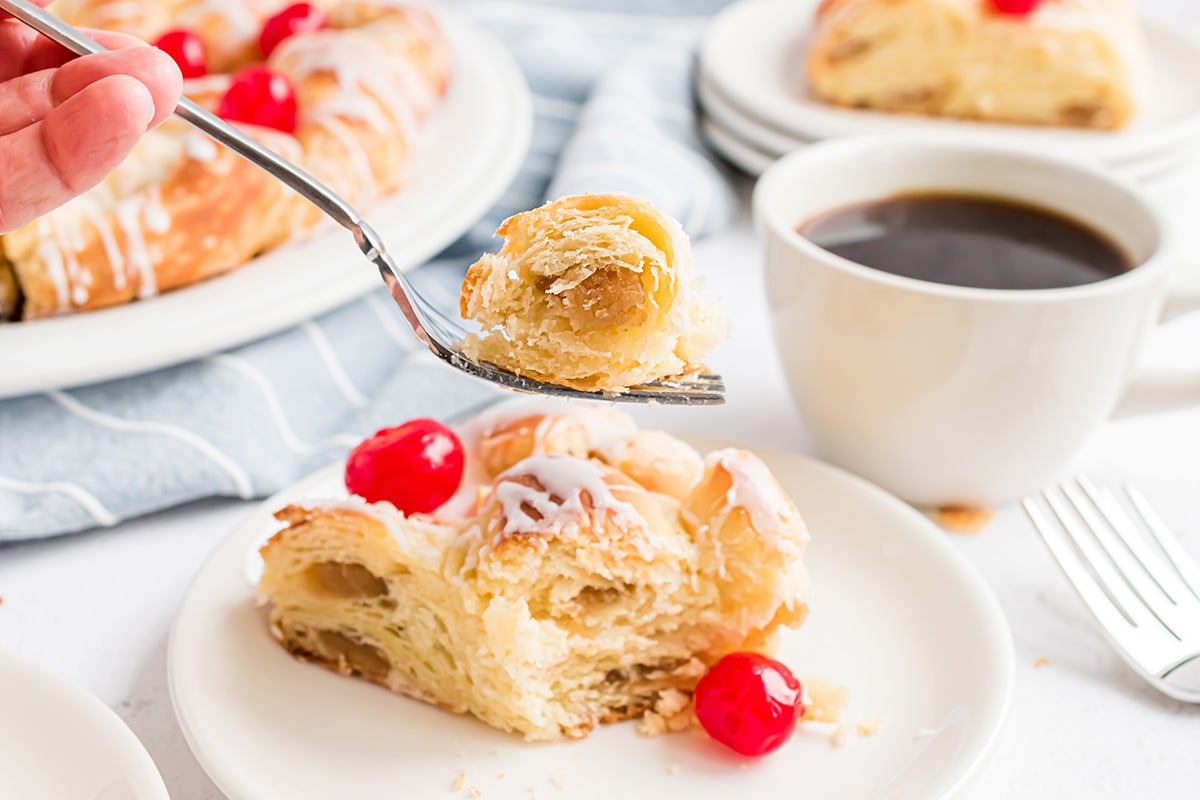 fork taking a bite of pastry with a cup of coffee 