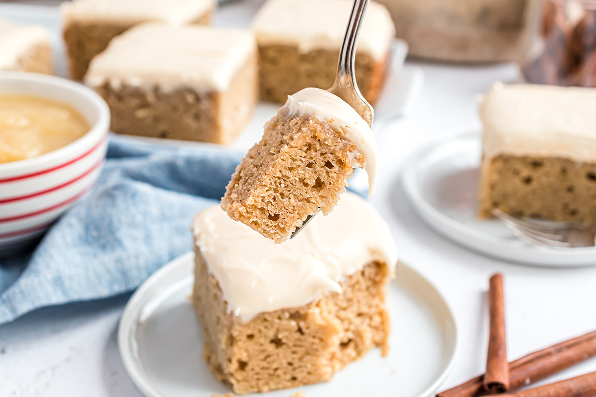fork holding a bite of applesauce cake with cream cheese frosting  