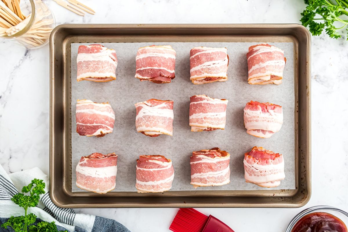 bacon wrapped meatballs on a baking sheet 