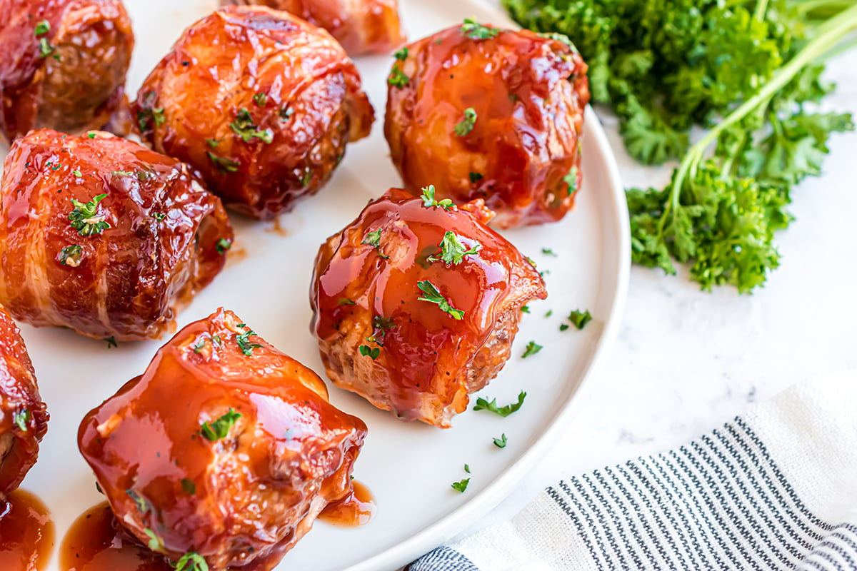 bacon wrapped meatballs on a white serving platter 