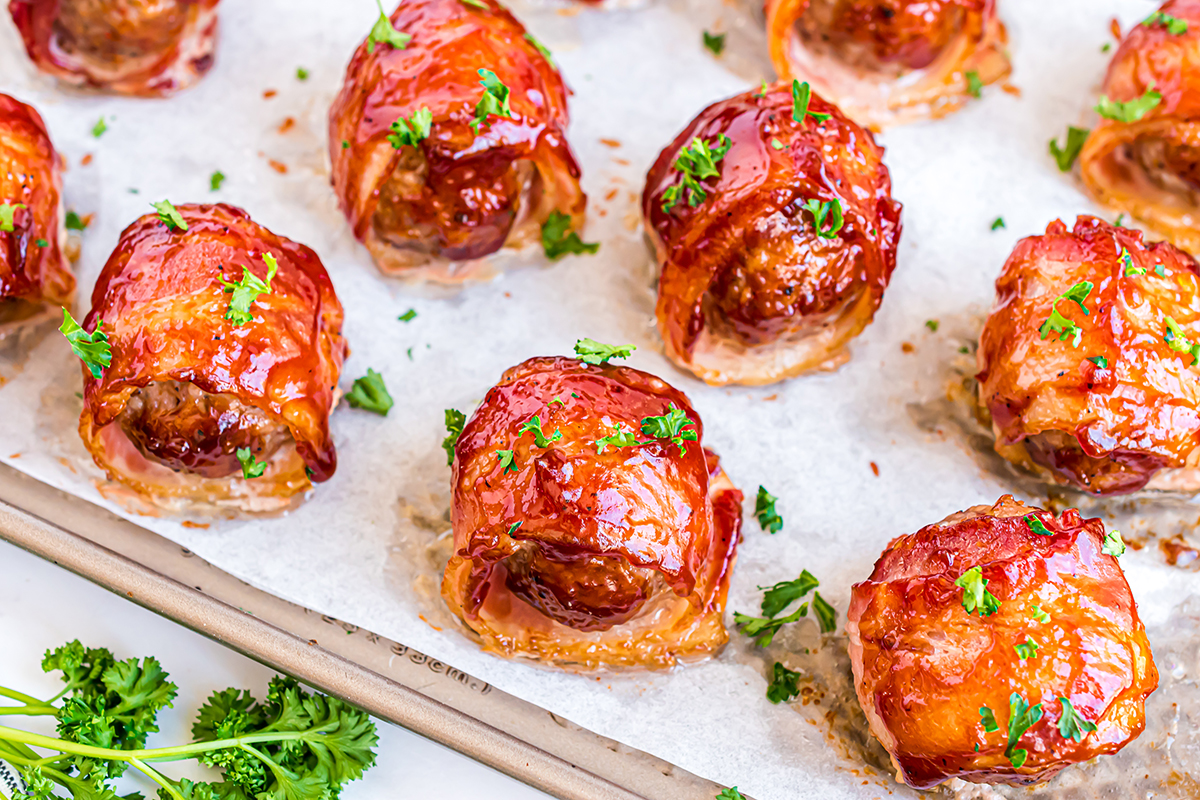 bacon wrapped meatballs on a parchment lined baking sheet 