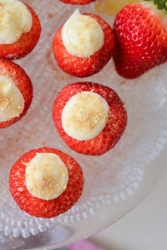 overhead of cheesecake stuffed strawberries on a glass serving plate