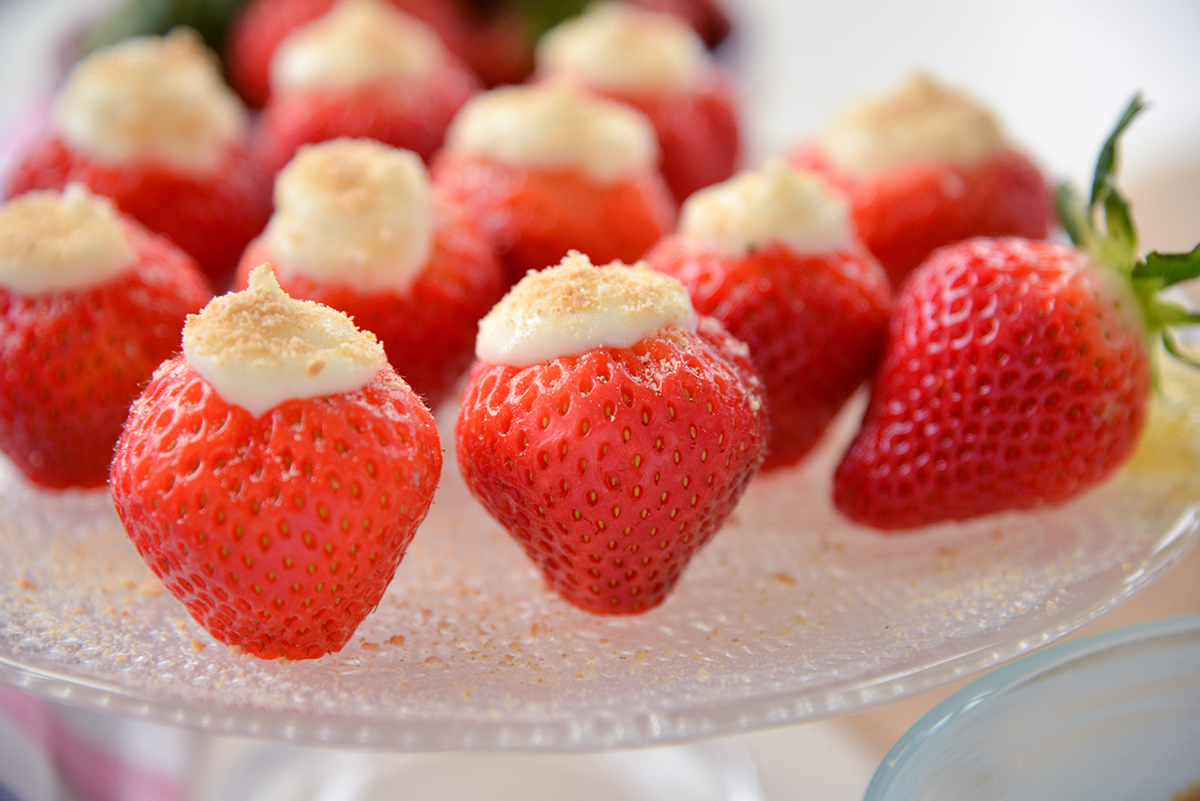 straight on shot of cheesecake stuffed strawberries on glass platter