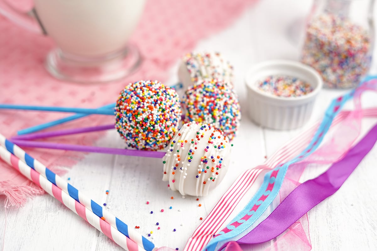 rainbow cake pops on their side with pink linen