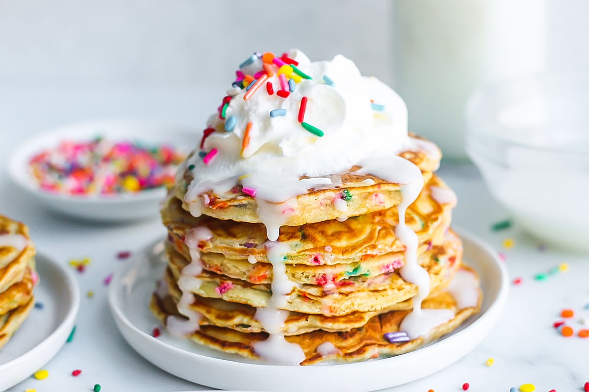 head on stack of pancakes with icing dripping down the sides 