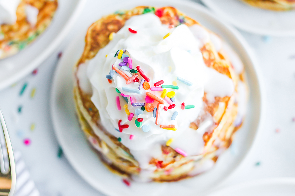 overhead of pancakes topped with whipped cream and icing 