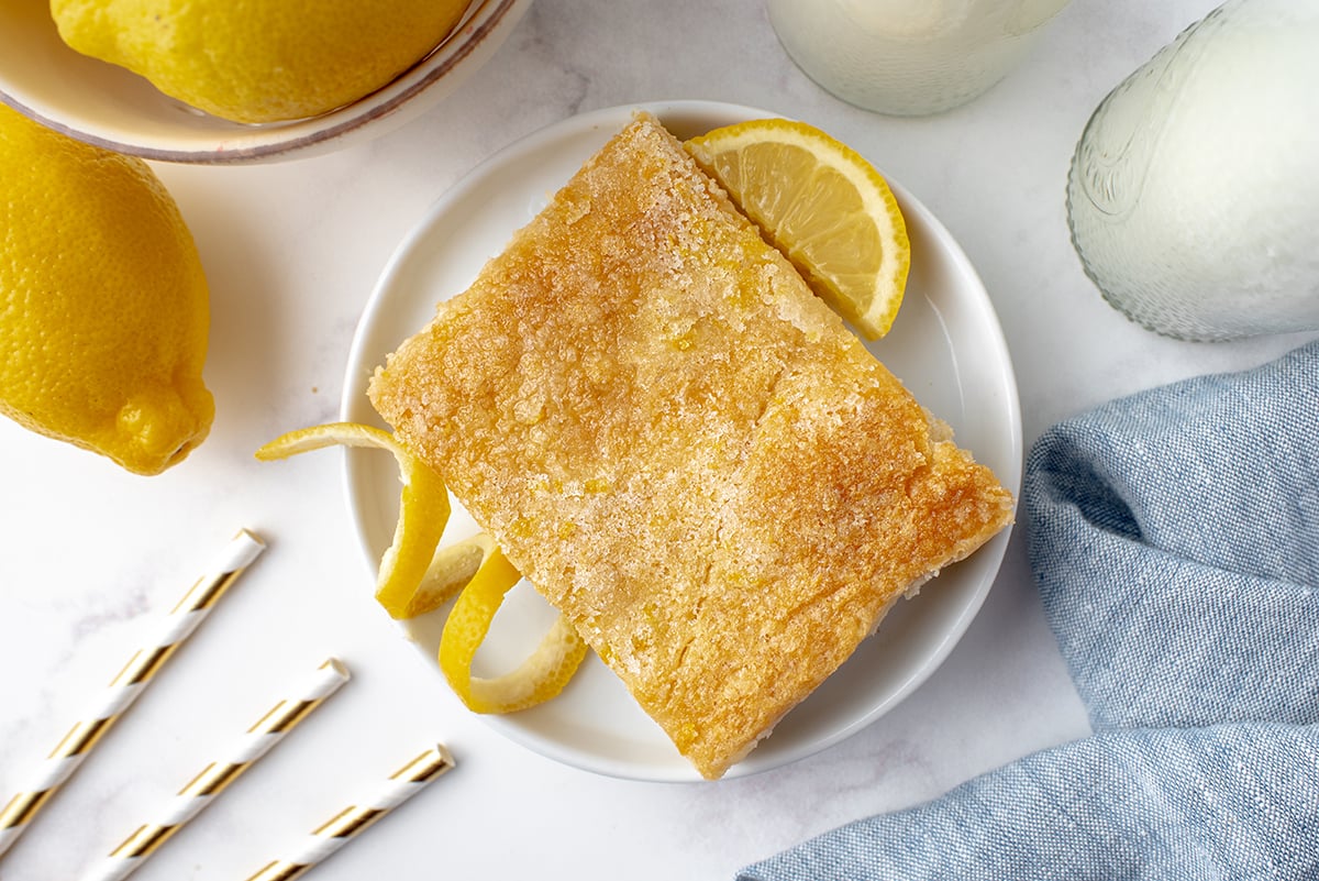 overhead of cheesecake bar on a small white plate with fresh lemons