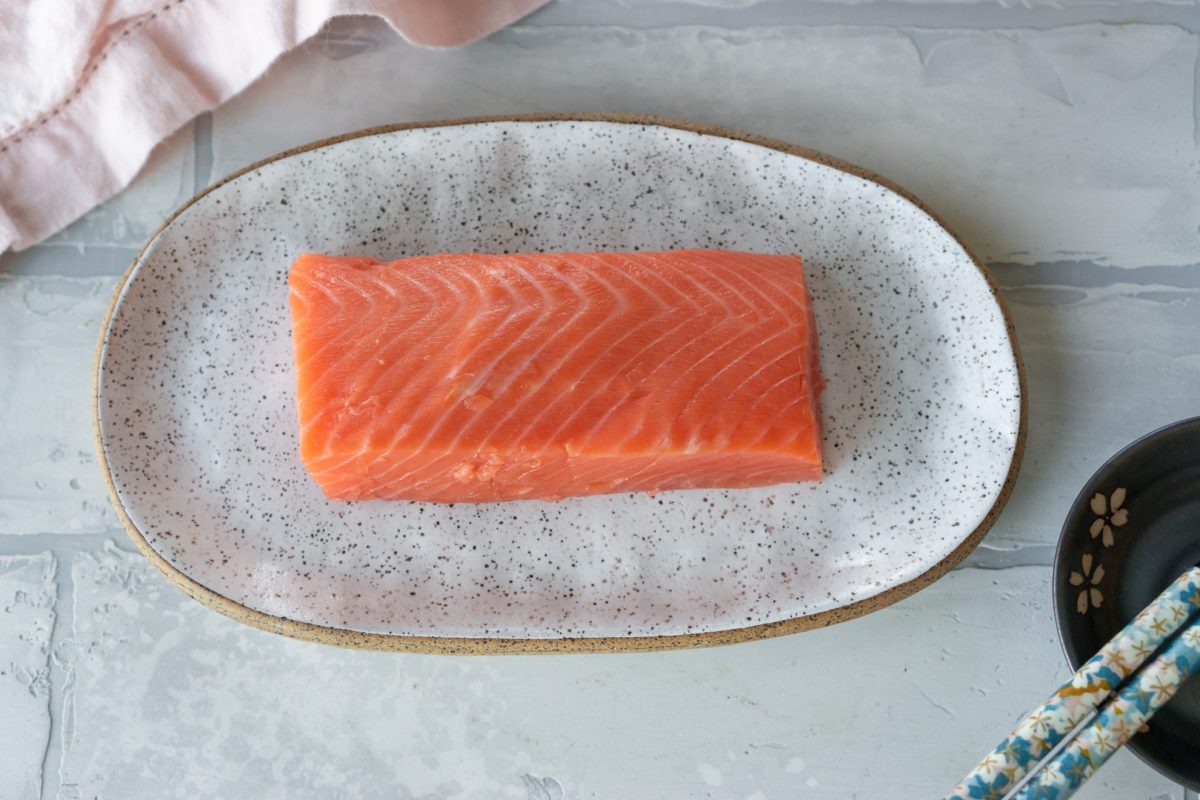 piece of raw salmon on a white speckled plate 