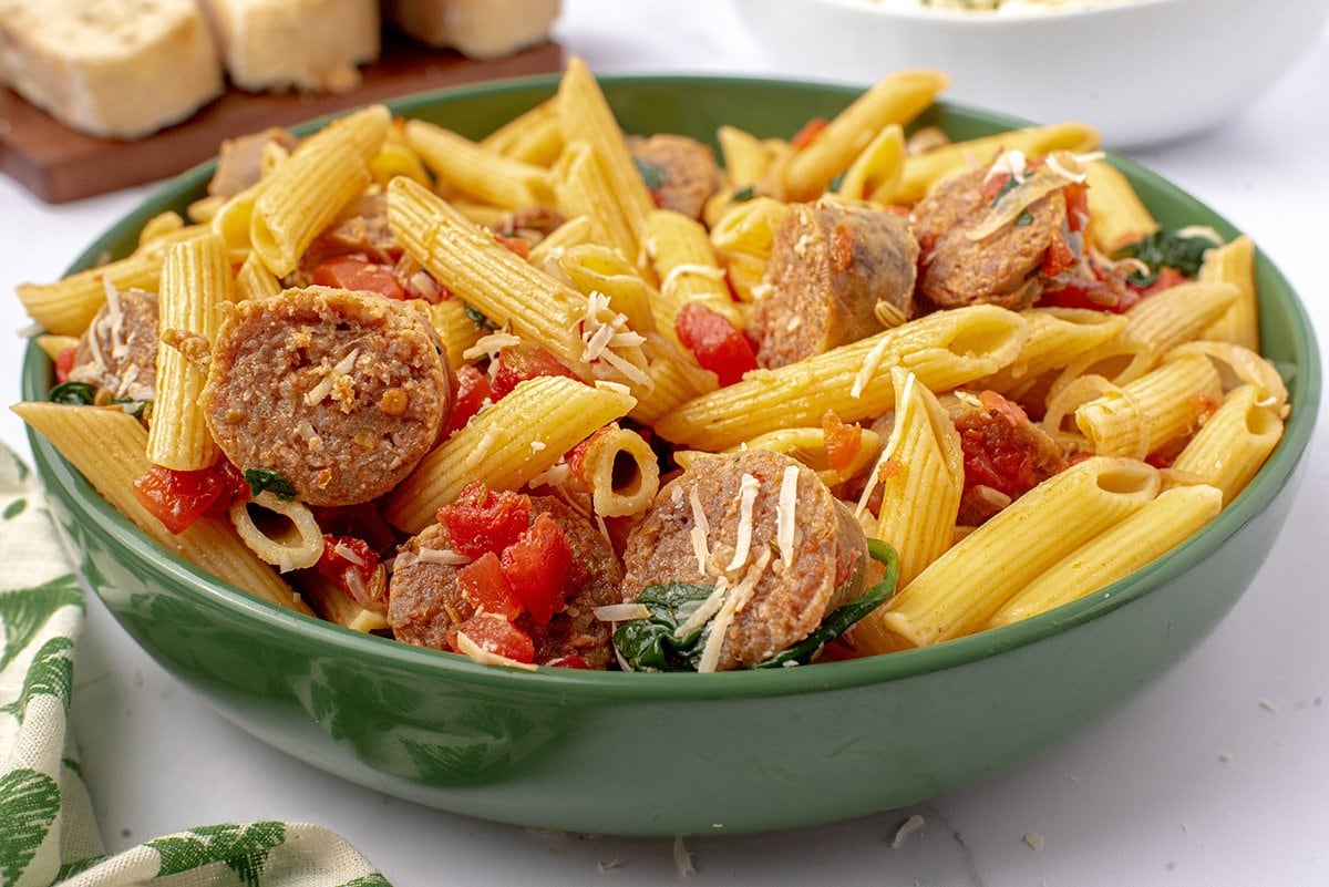 angle view of sausage pasta in a green bowl 