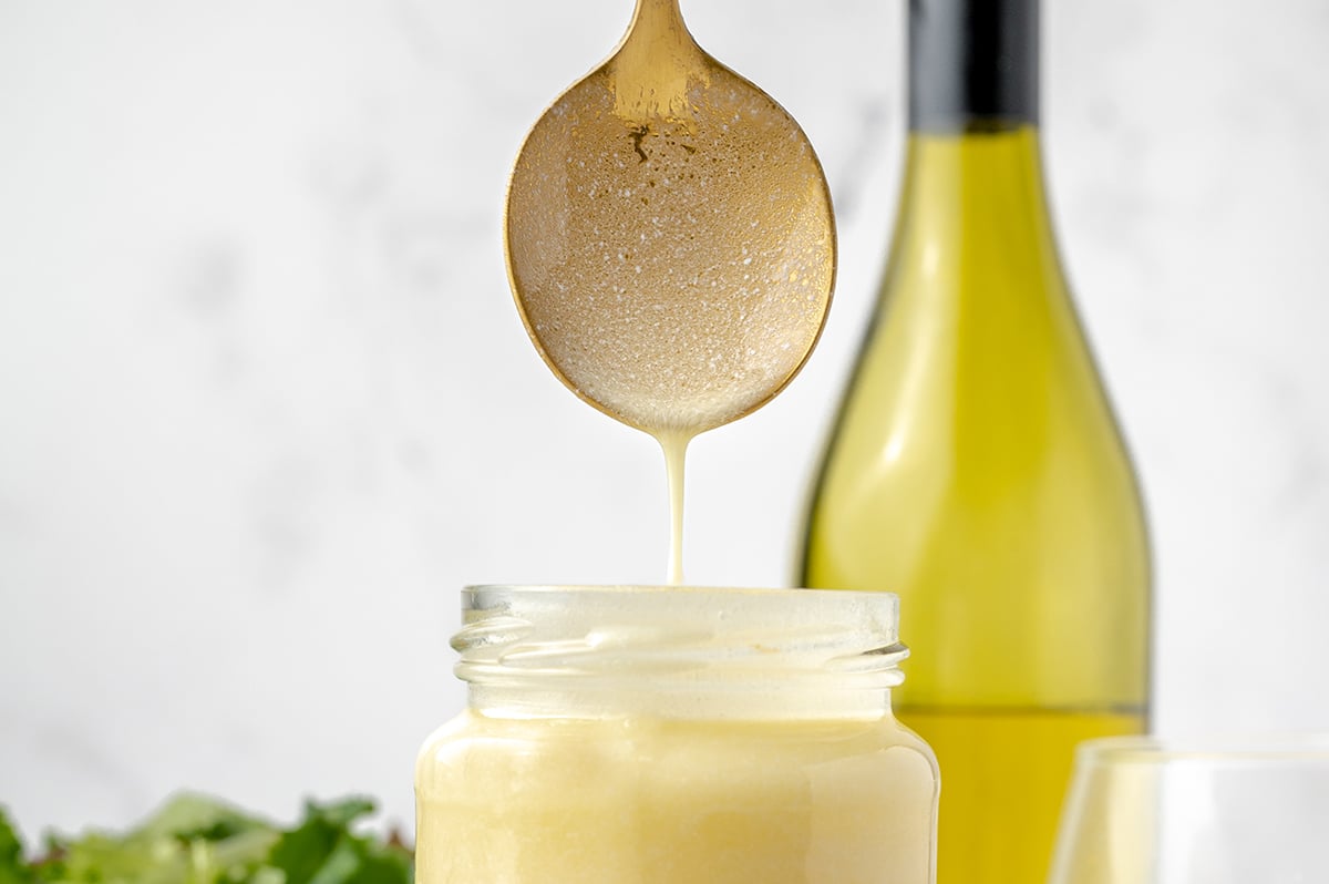 straight on shot of spoon in jar of beurre blanc sauce