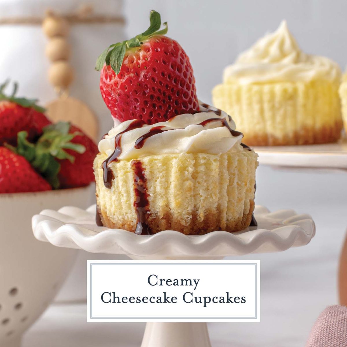 close up of individual cheesecake with strawberries in the background