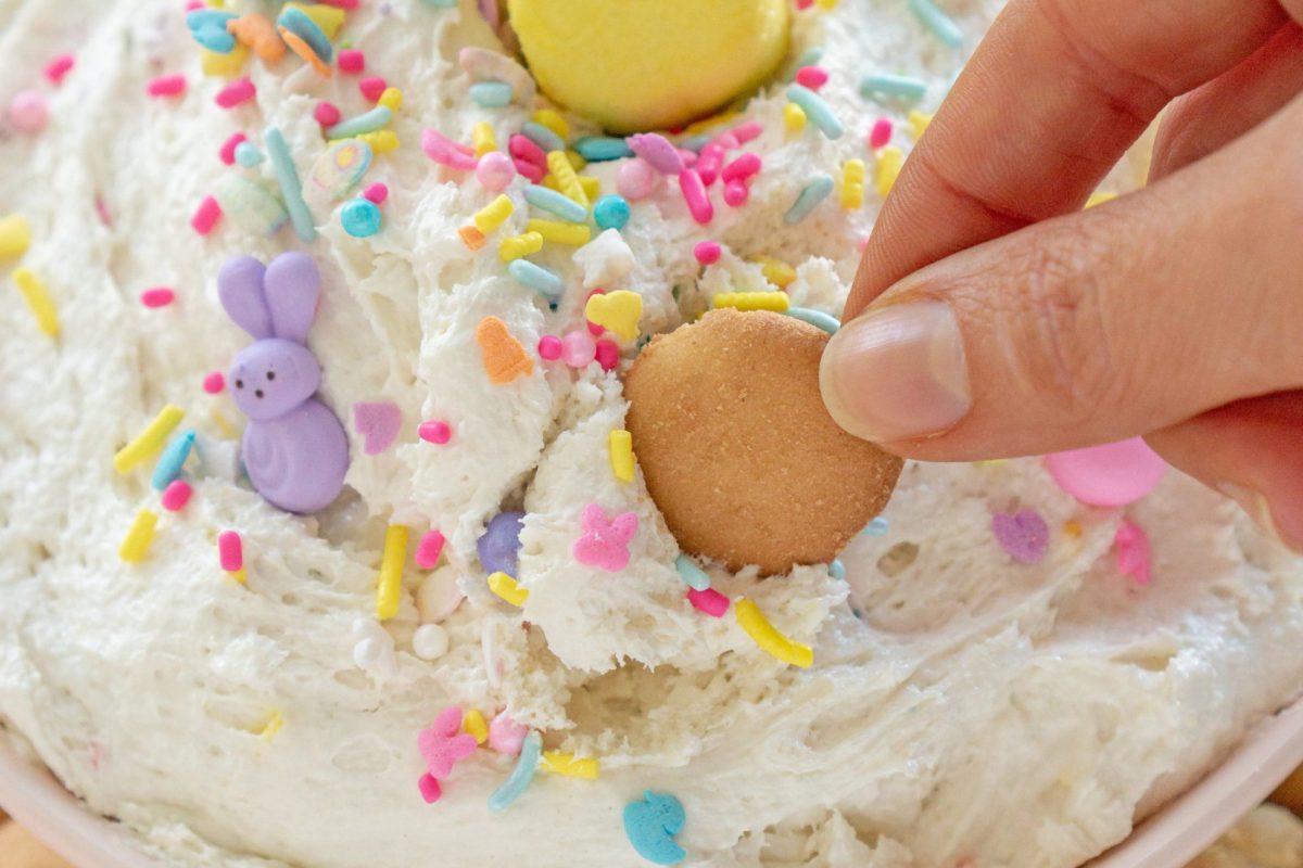 hand dipping vanilla wafer in a cake batter dip 