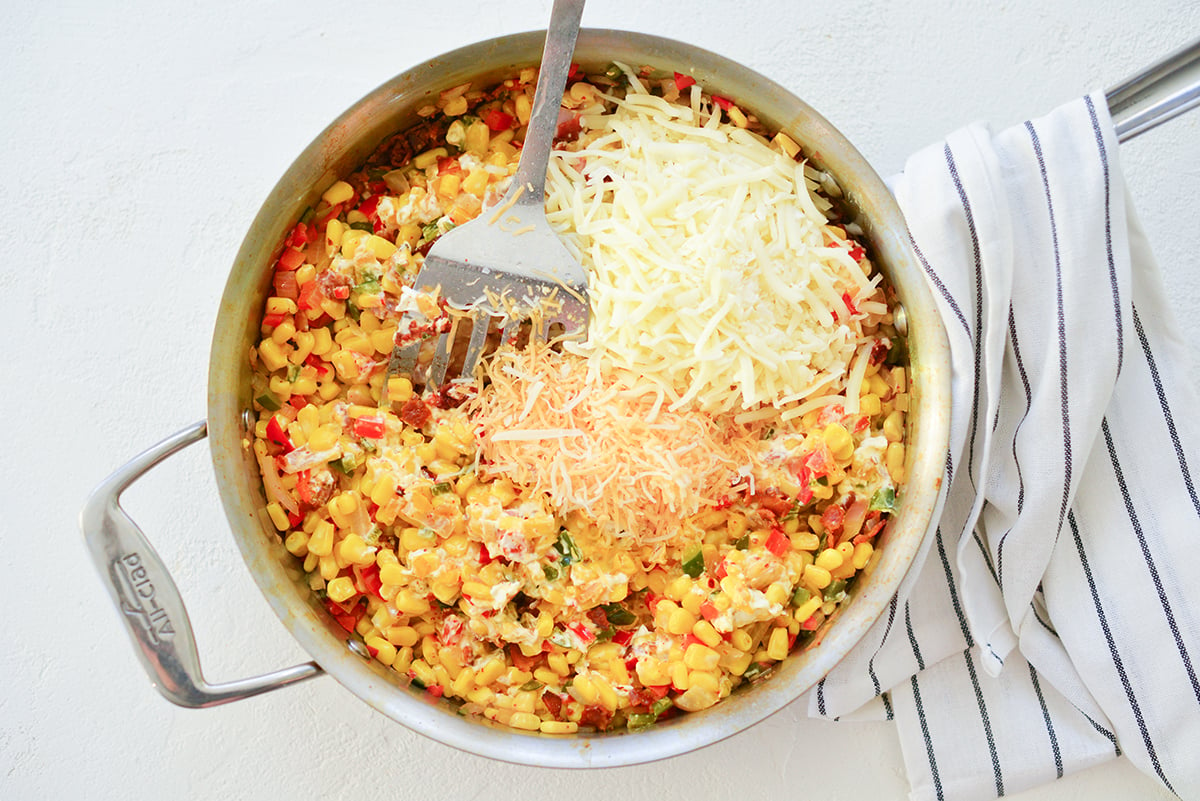 shredded cheese being added to corn dip 