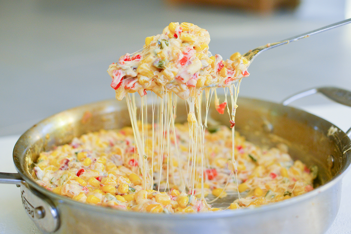 spoon digging out creamy hot corn