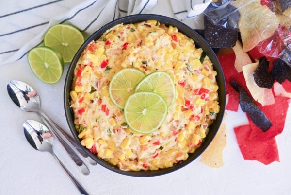 overhead of hot corn dip with limes and chips