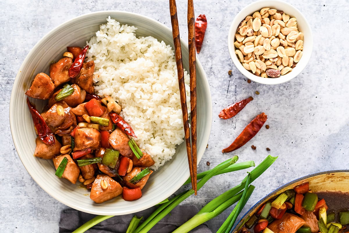 spicy chinese chicken being served with scallions and peanuts 