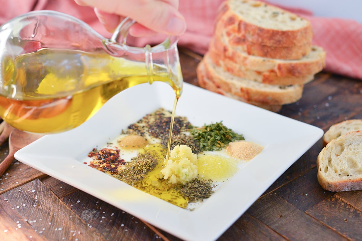 olive oil drizzling into a plate of herbs and spices 