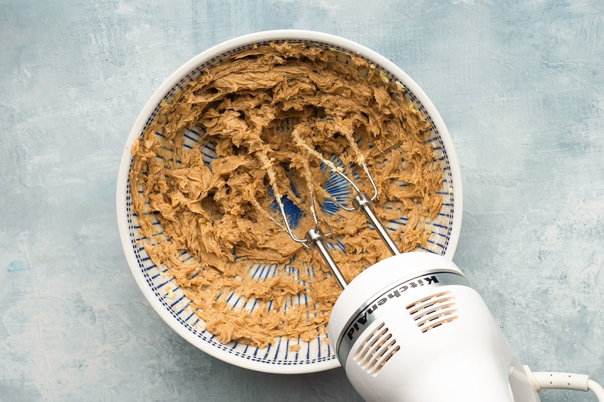 hand mixer in a mixing bowl with brown butter 