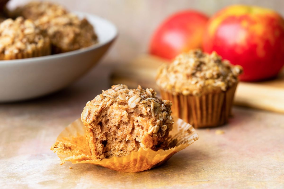 recipe for Apple sauce muffins with bite taken out of it and a bowl of muffins and apples in the background