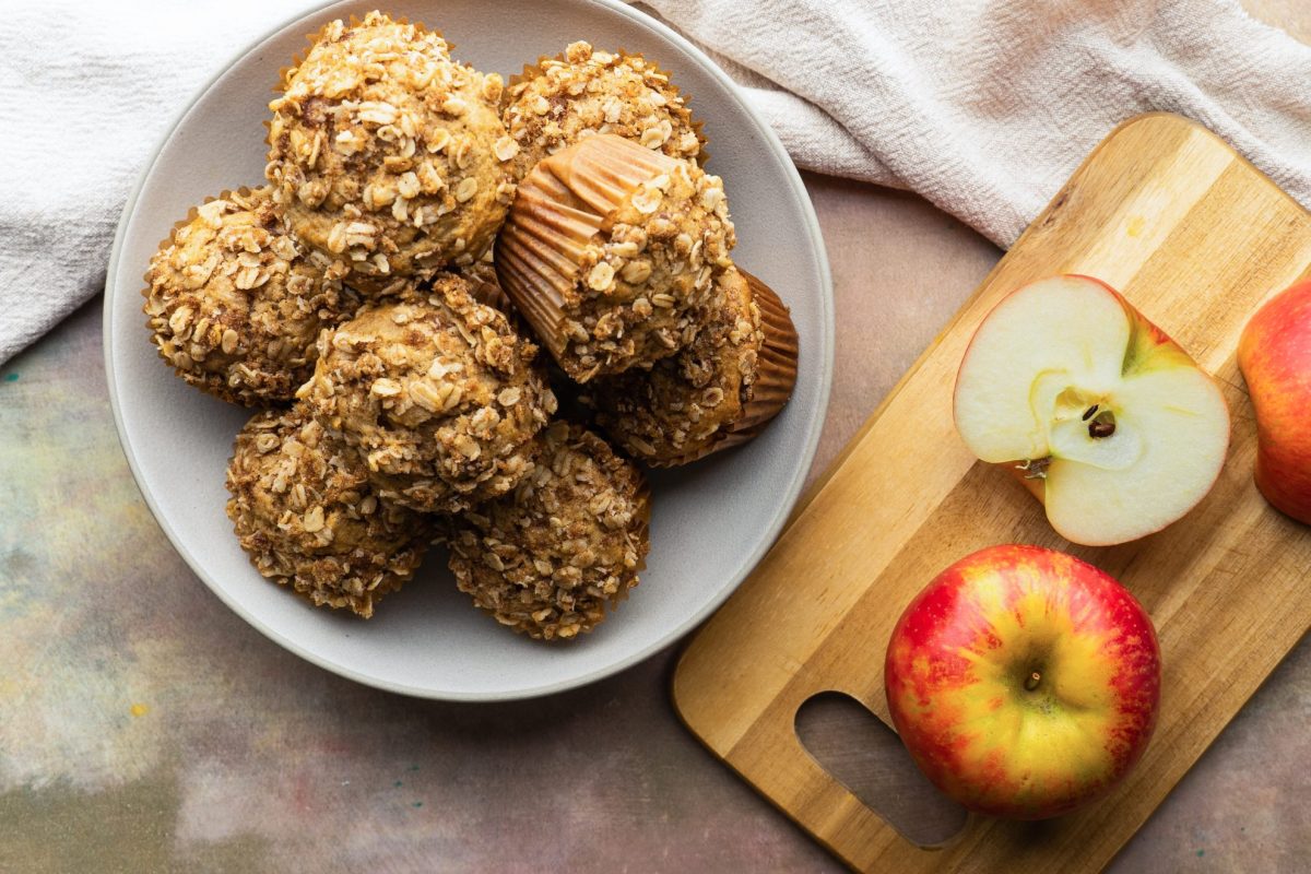 overhead shot of a bowl of simple applesauce muffins with a cut apple on a cutting board next to it