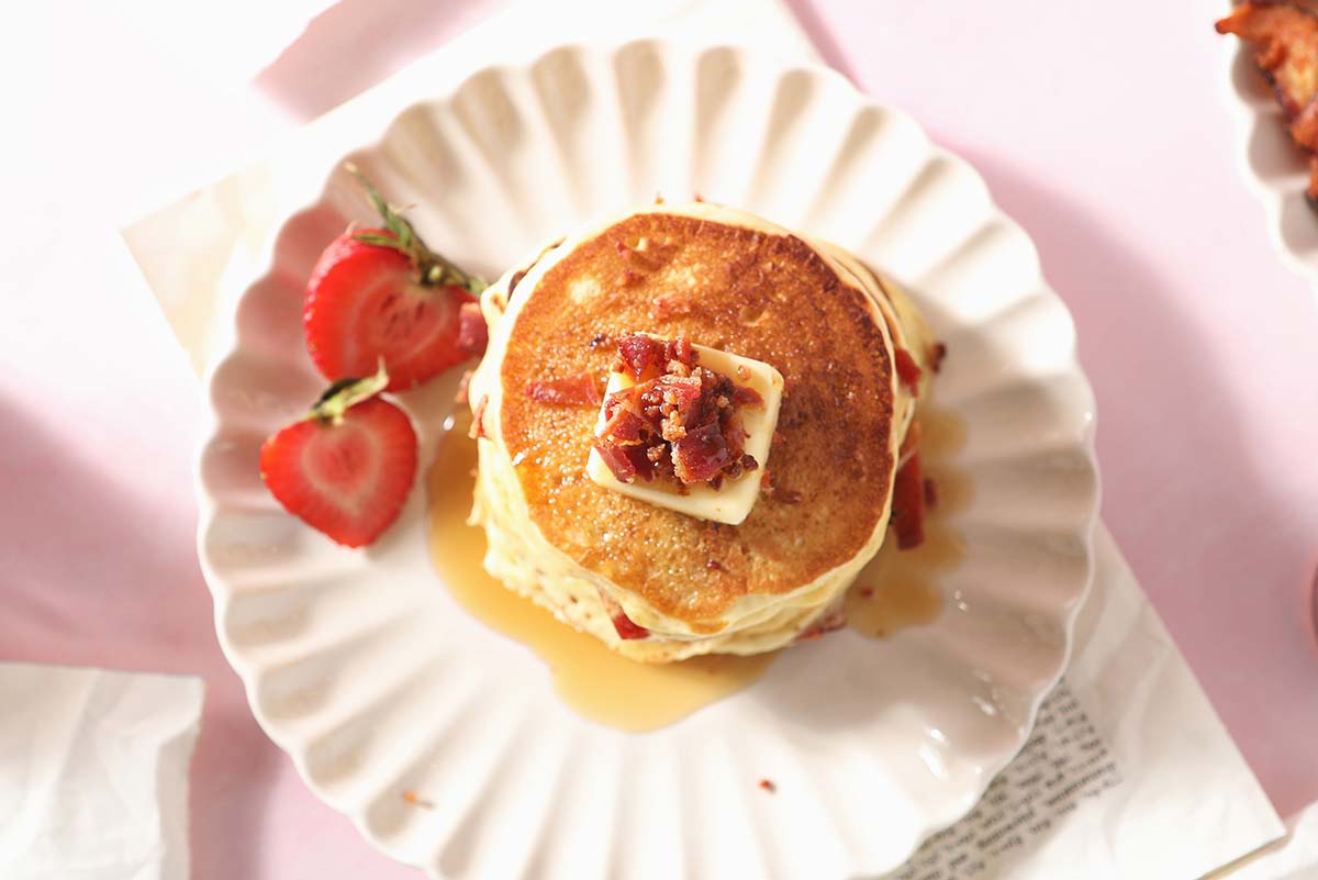 overhead stack of pancakes with butter and bacon 