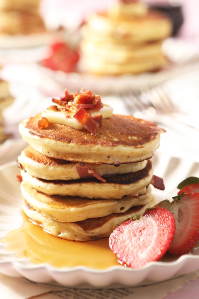 large stack of bacon pancakes with strawberry topping