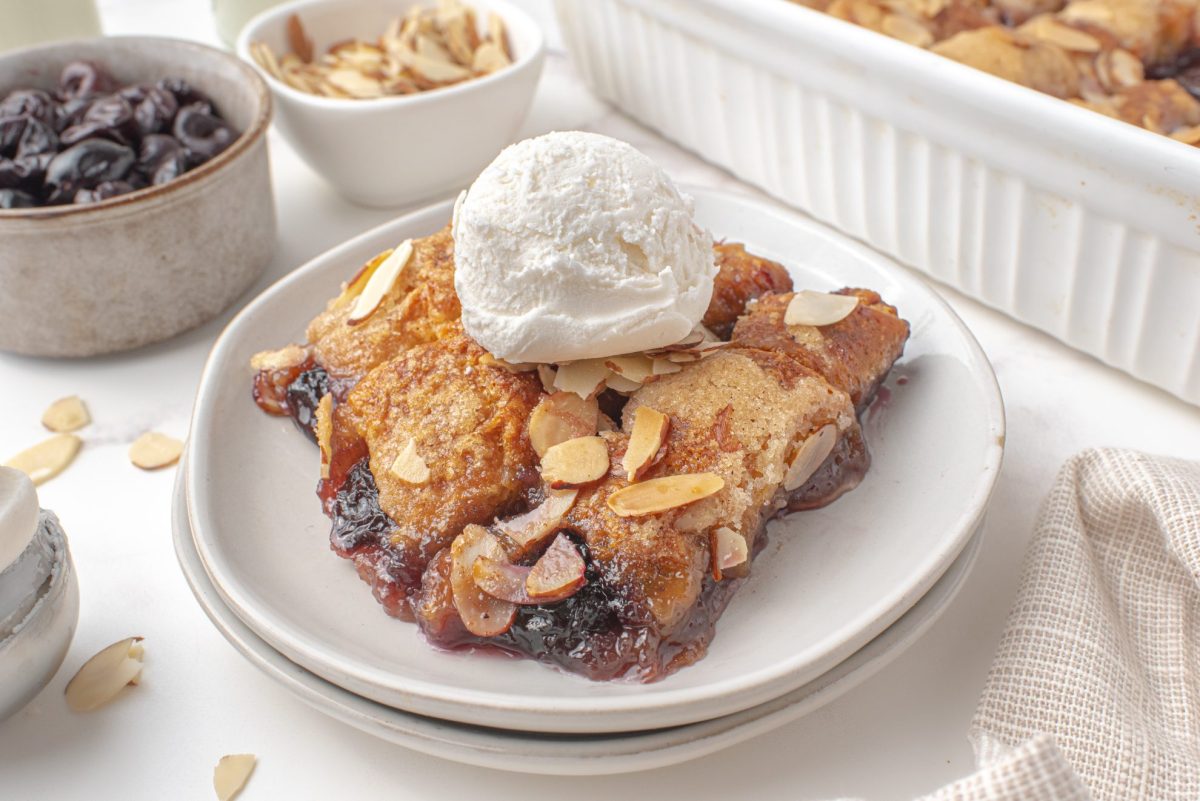 Slice of cherry dumpling casserole topped with ice cream on a white plate