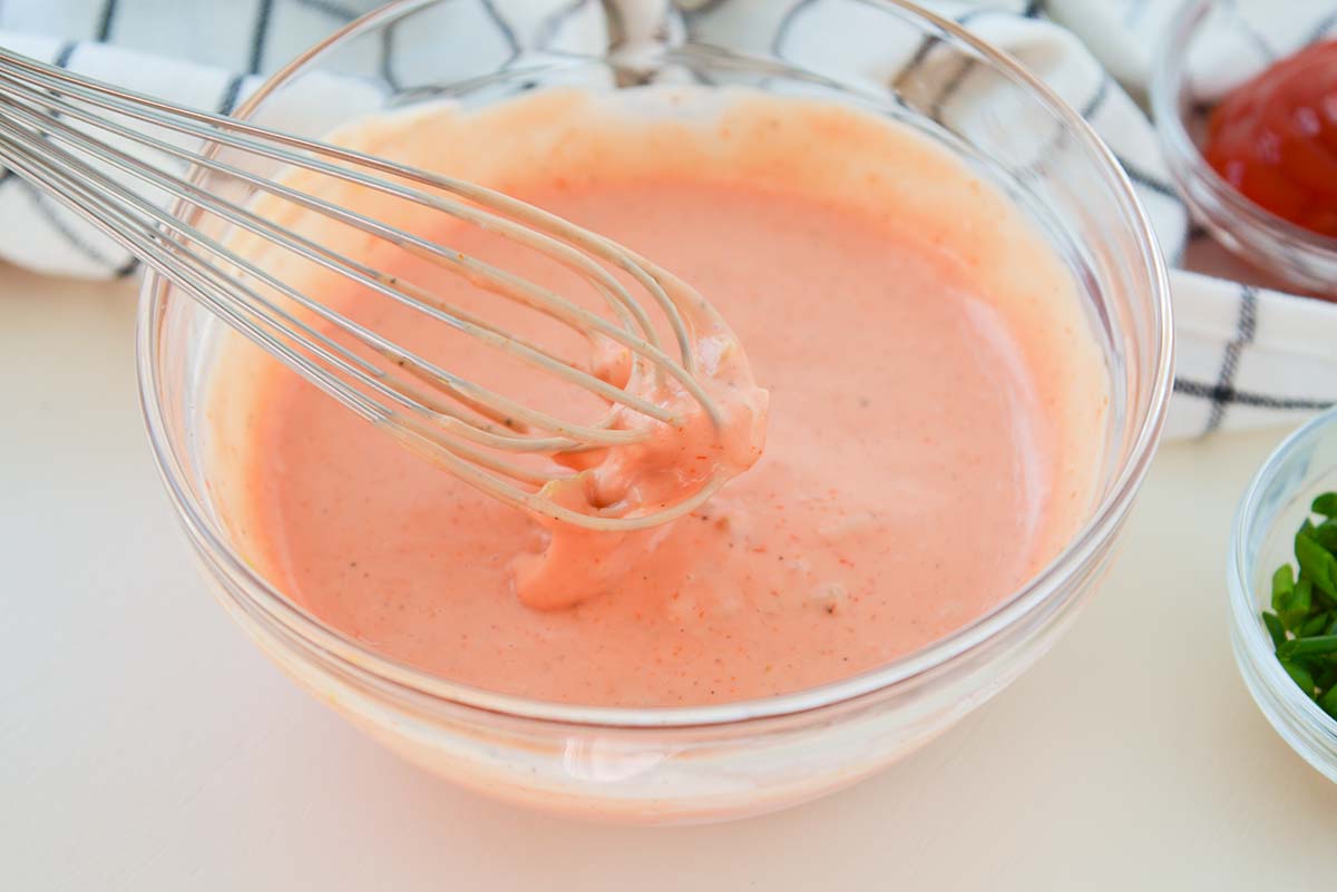 close up of a whisk with thick and creamy fry sauce on it 