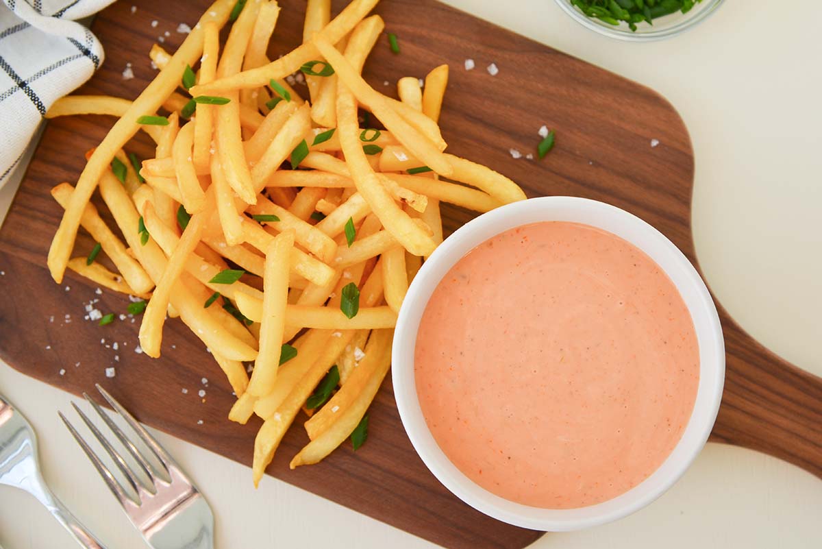 overhead bowl of fry sauce with homemade french fries on a wood cutting board 