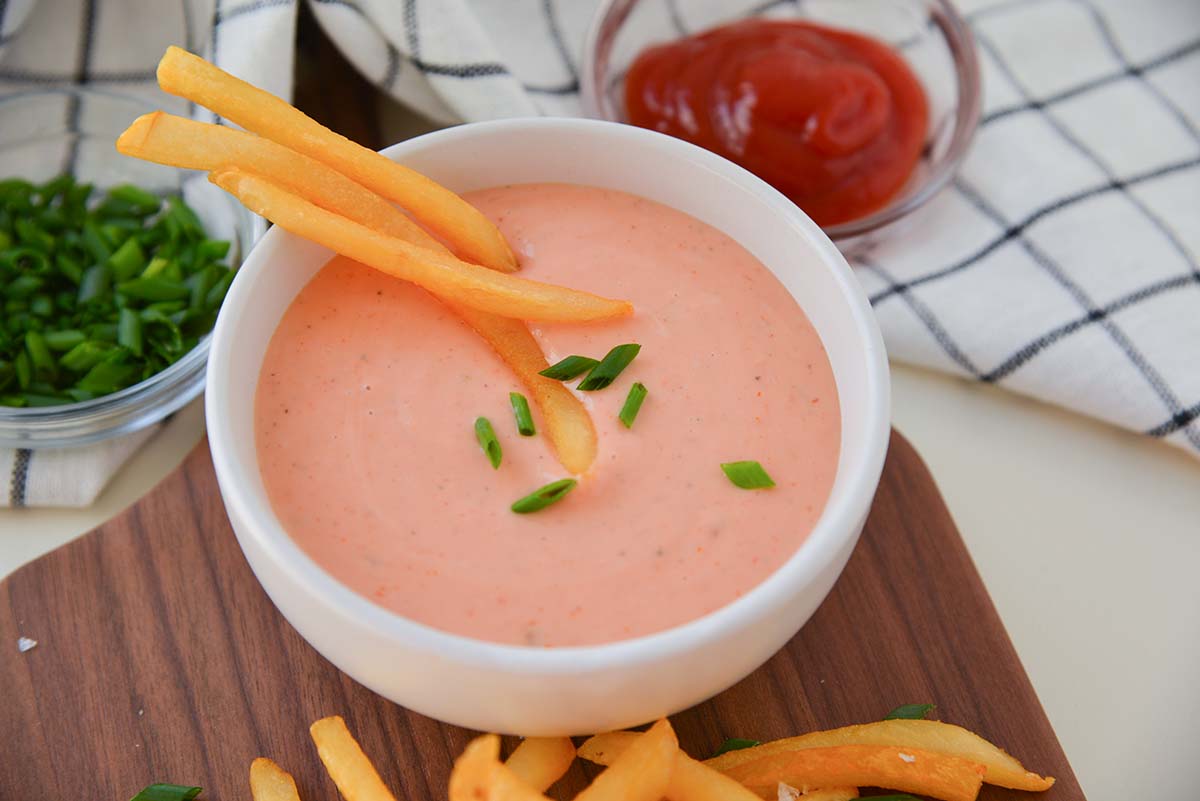 angled shot of three fries in bowl of fry sauce