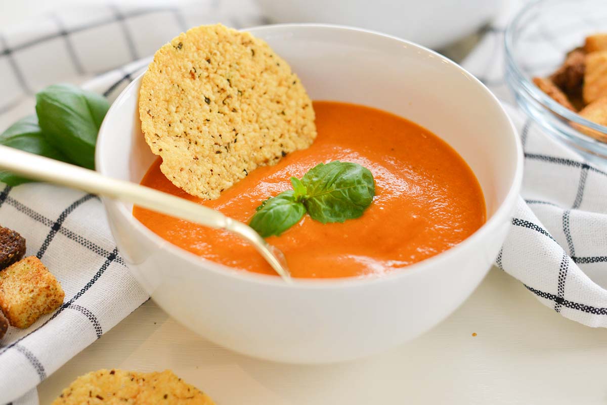 close up of a bowl of red soup with black and white linens 