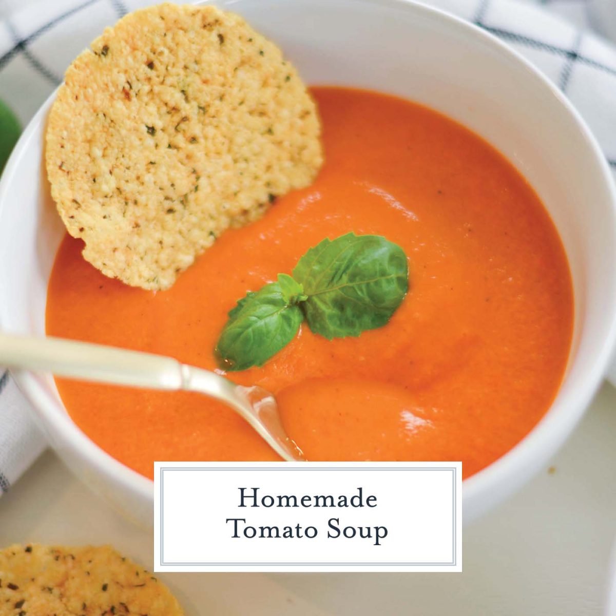 close up bowl of tomato soup with croutons, basil and parmesan crisp