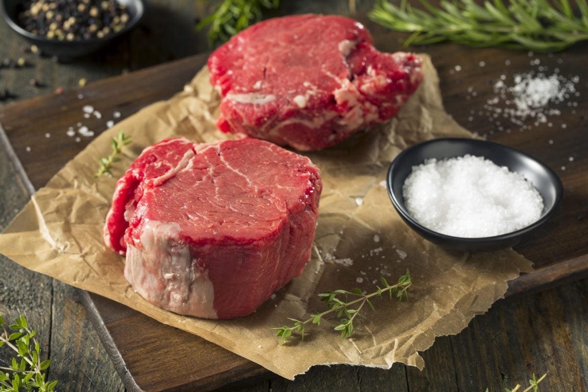 two raw filet mignon steaks on brown butcher paper 