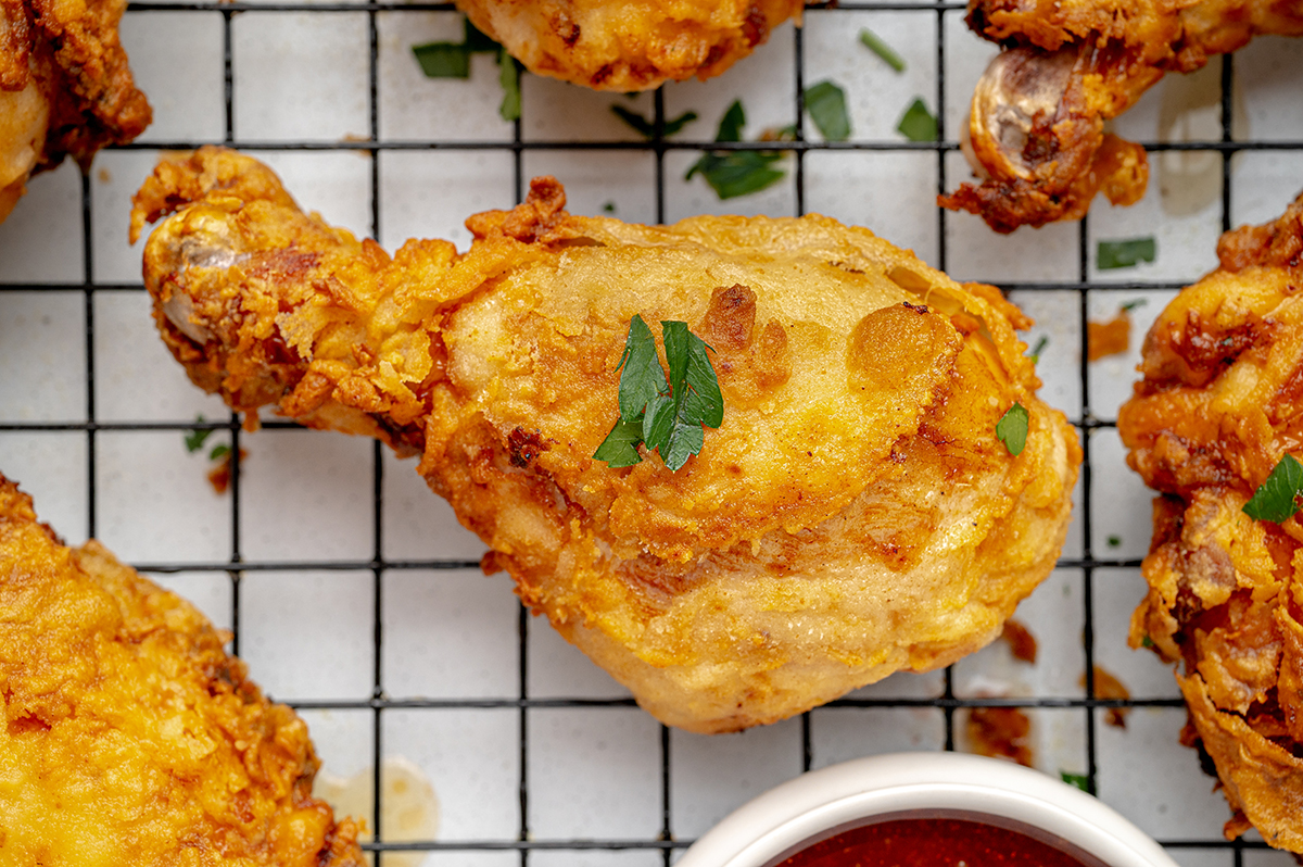 close up of buttermilk fried drumstick on wire rack