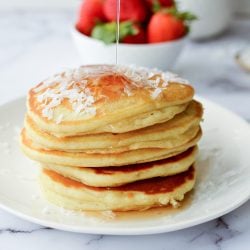 stack of coconut pancakes with syrup poured on top