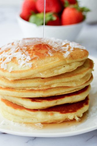 stack of coconut pancakes with syrup poured on top