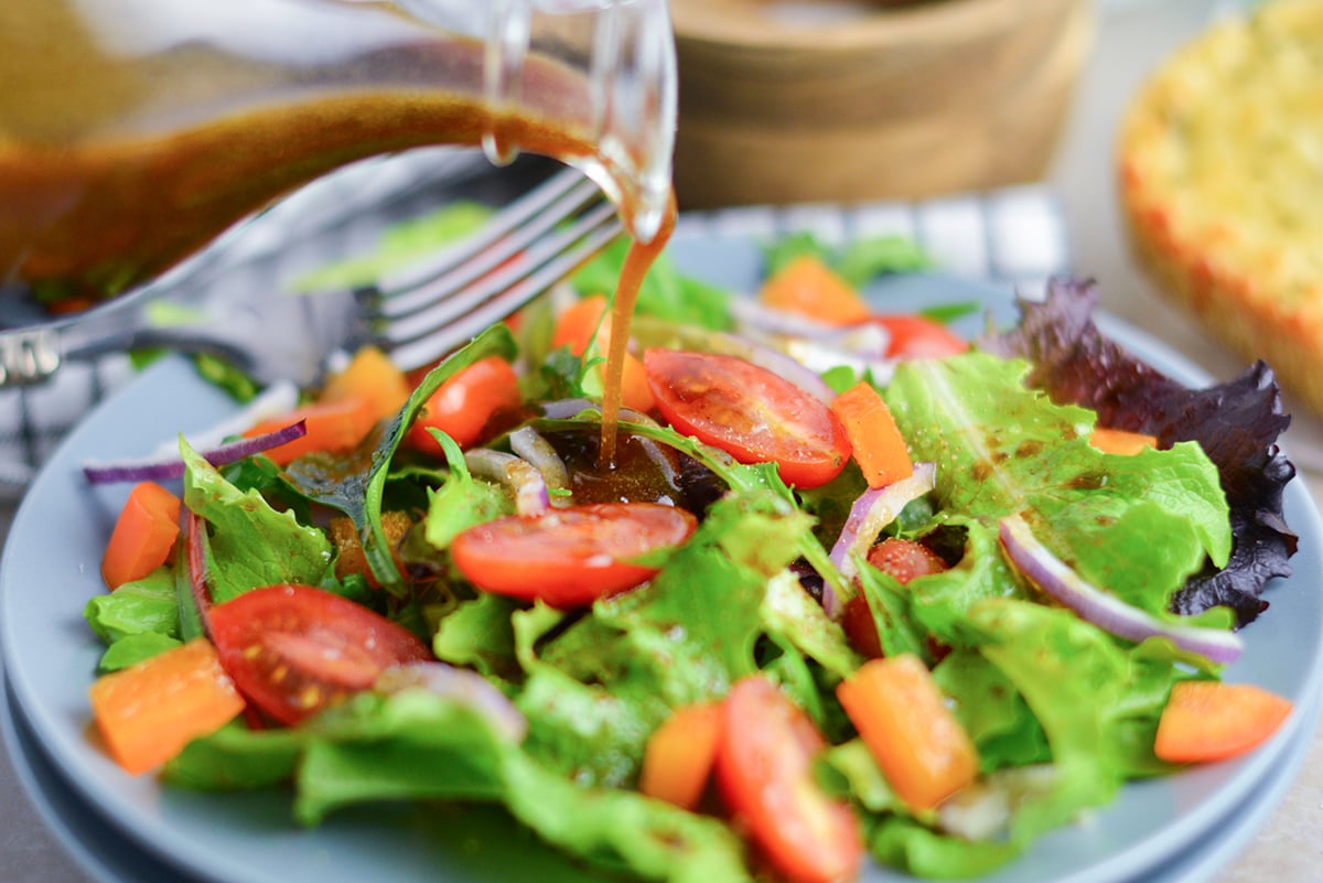 garlic balsamic vinaigrette poured onto salad on blue plate