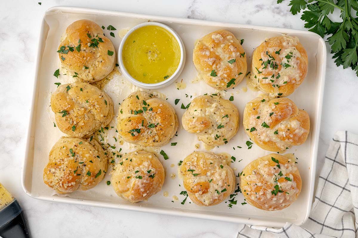tray of homemade garlic knots with a bowl of garlic butter 