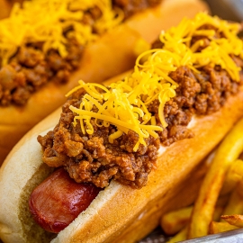 close up of two chili dogs on a tray with fries