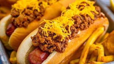 close up of two chili dogs on a tray with fries