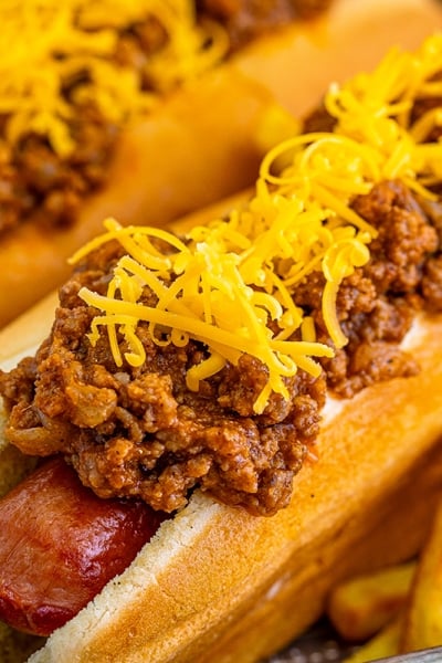 close up of two chili dogs on a tray with fries