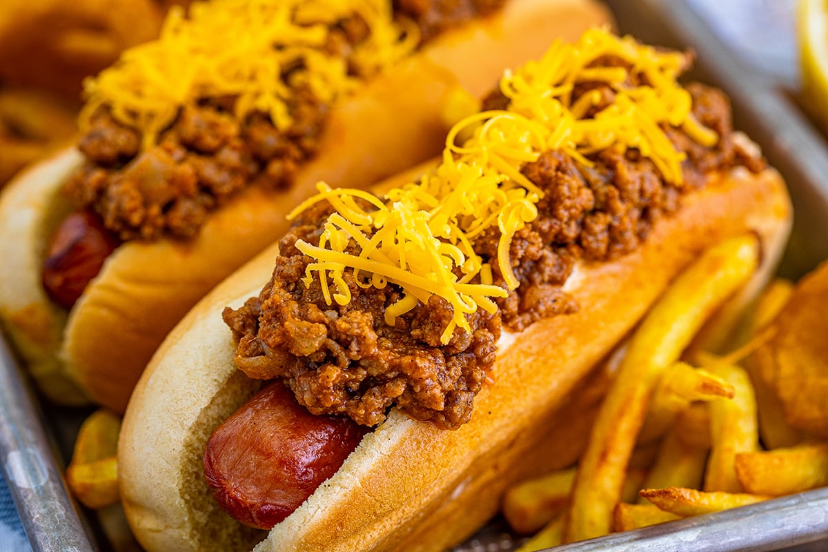 close up of two chili dogs on a tray with fries