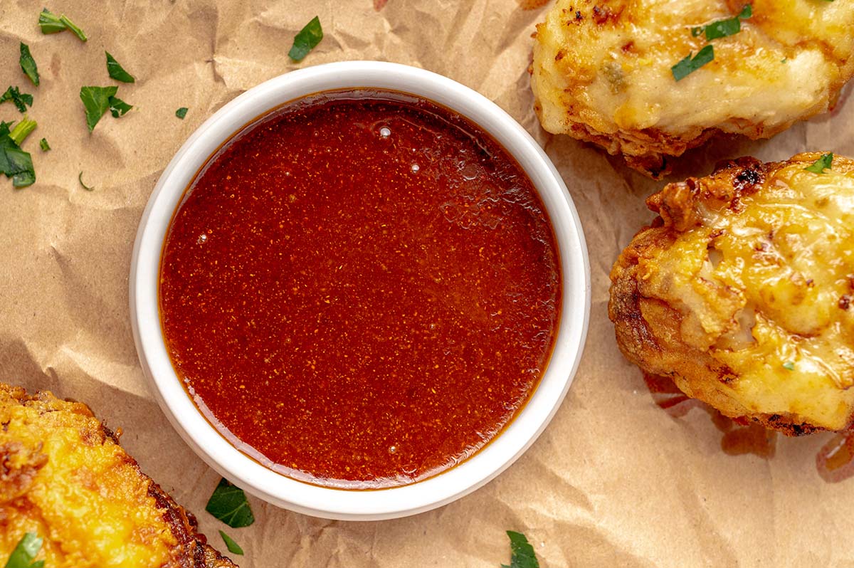 bowl of red hot sauce with fried chicken around it 