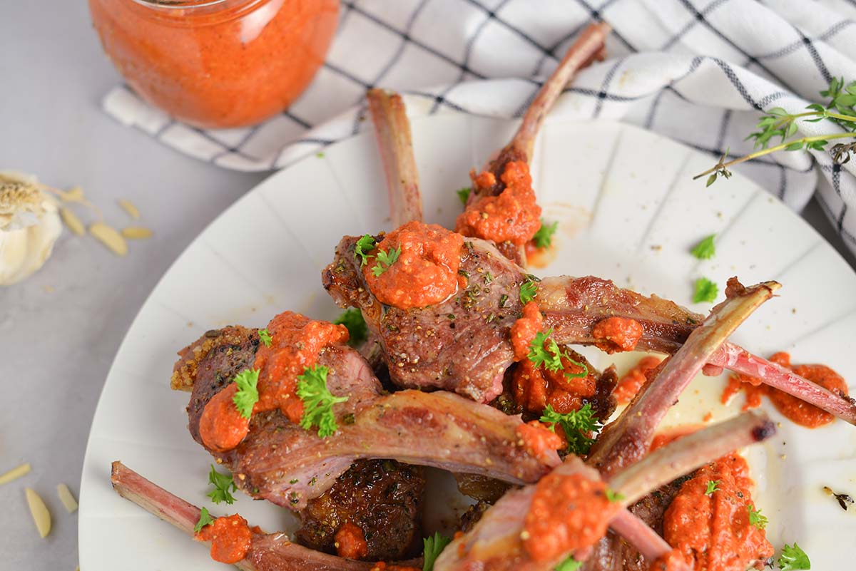 close up of pan seared lamb chops topped with sauce 