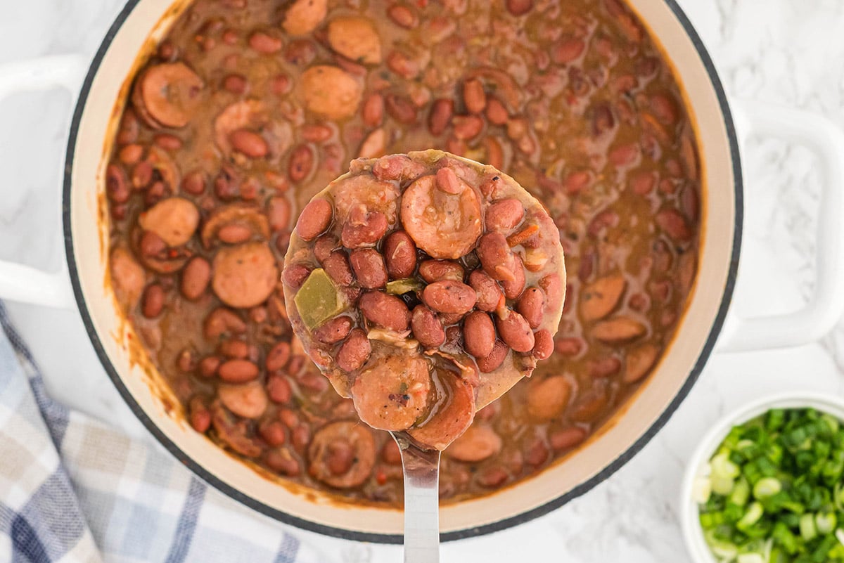 ladle holding red beans and rice with seasonings 