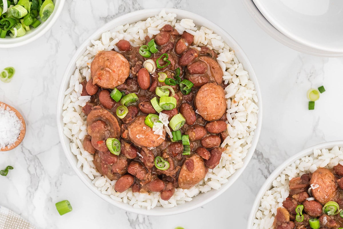overhead white bowl of red beans and rice with scallion garnish 