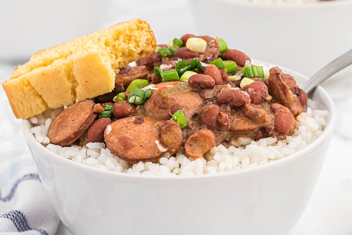 angle view of beans and sausage over rice with cornbread 