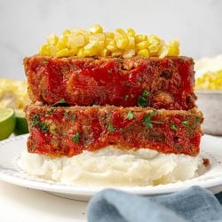 two slices of meatloaf over mashed potatoes topped with corn