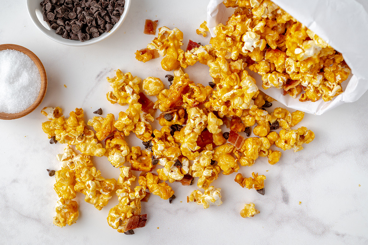 overhead shot of bacon caramel popcorn spilled out of white paper bag