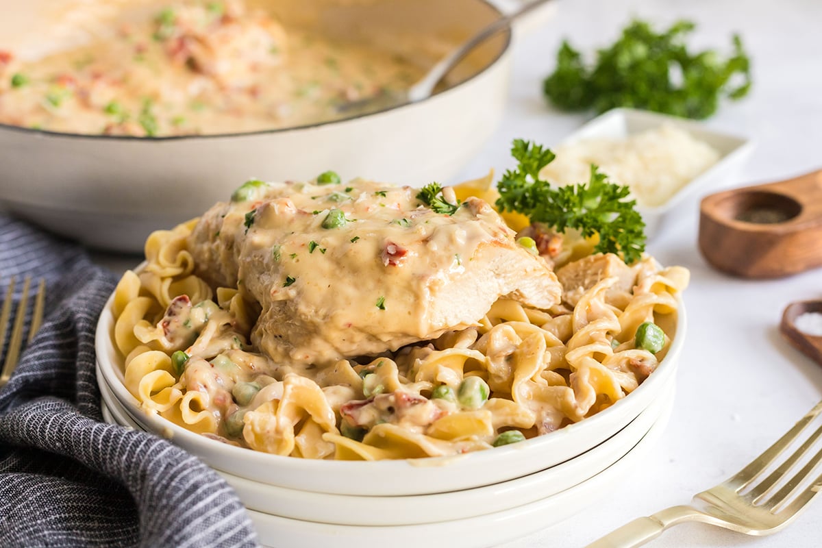 creamy garlic chicken over noodles on white plate